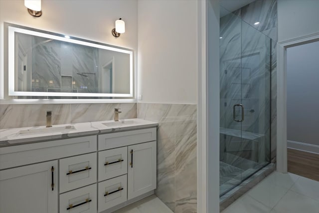 bathroom featuring vanity, a shower with shower door, and tile walls