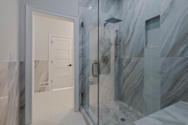 bathroom featuring a shower with shower door, tile patterned floors, and tile walls