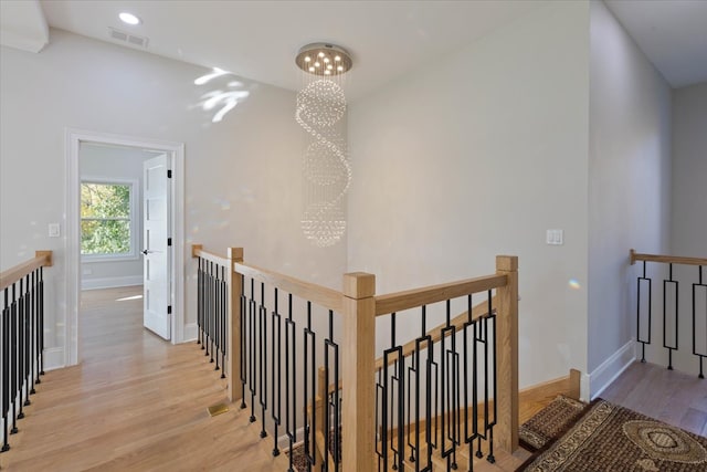 hall with light hardwood / wood-style floors and a chandelier