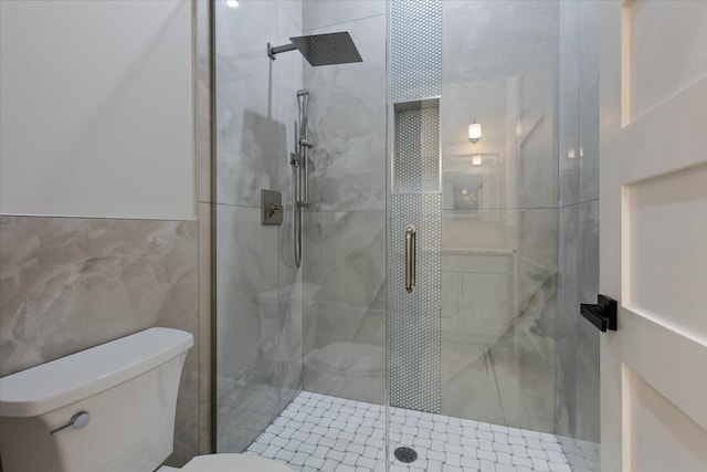 bathroom featuring toilet, tile walls, and a shower with shower door