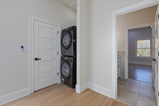 laundry room with stacked washer and clothes dryer and light hardwood / wood-style floors