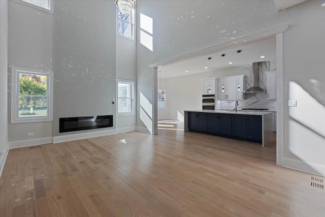 unfurnished living room with hardwood / wood-style flooring, sink, and a high ceiling