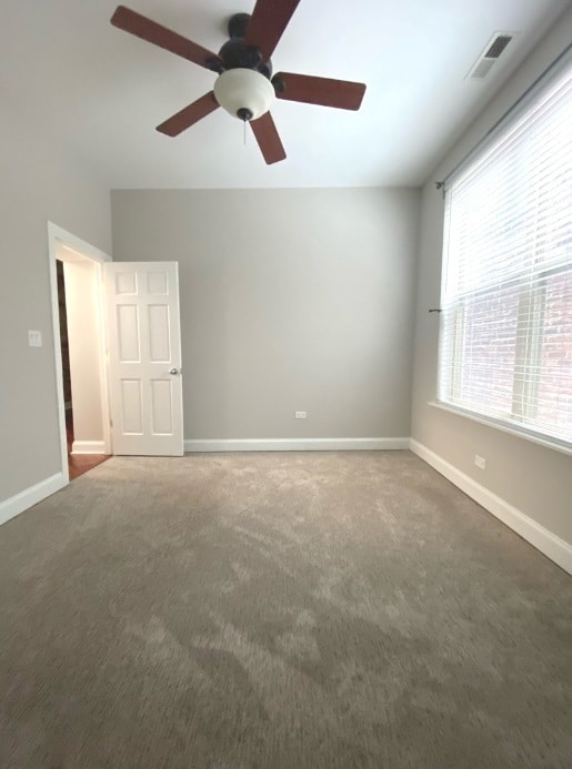 empty room with dark colored carpet and ceiling fan