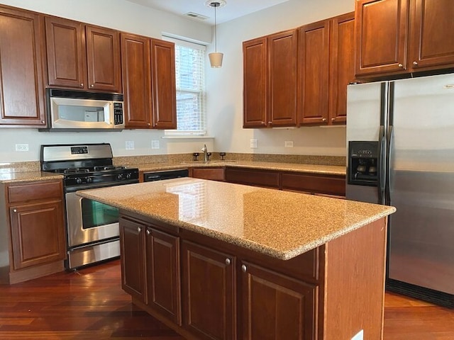 kitchen with hanging light fixtures, dark hardwood / wood-style flooring, stainless steel appliances, sink, and a center island