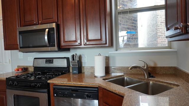 kitchen featuring stainless steel appliances, sink, and light stone counters