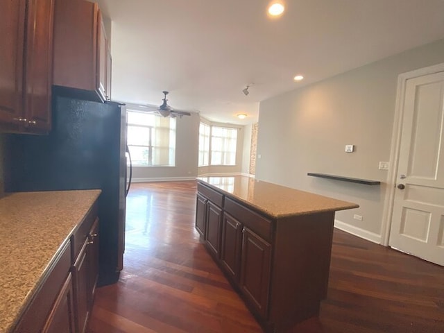 kitchen featuring a center island, dark hardwood / wood-style floors, black refrigerator, and ceiling fan