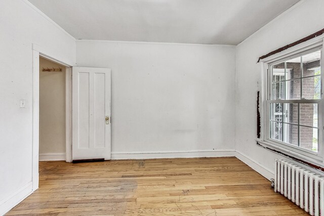 unfurnished room with crown molding, radiator heating unit, and light hardwood / wood-style floors