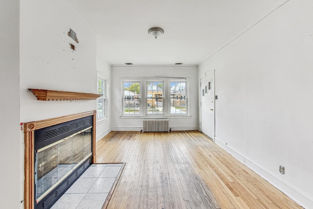 unfurnished living room with light hardwood / wood-style flooring and radiator heating unit