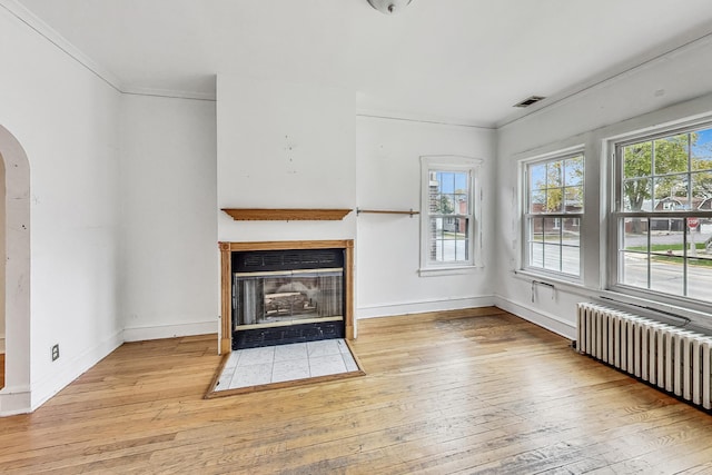 unfurnished living room featuring radiator, ornamental molding, and light hardwood / wood-style flooring