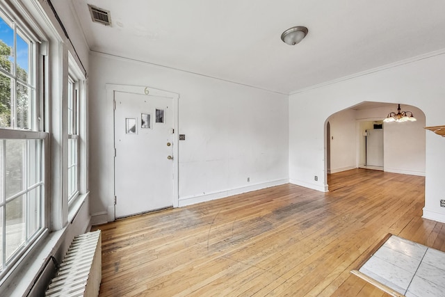 interior space featuring ornamental molding, an inviting chandelier, radiator heating unit, and light wood-type flooring