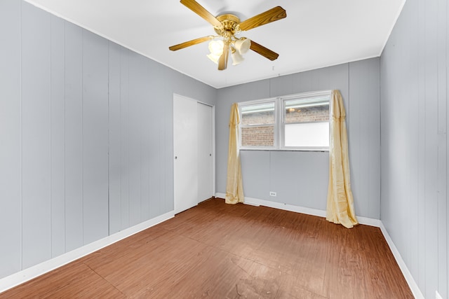 unfurnished room with ceiling fan, hardwood / wood-style flooring, and wooden walls