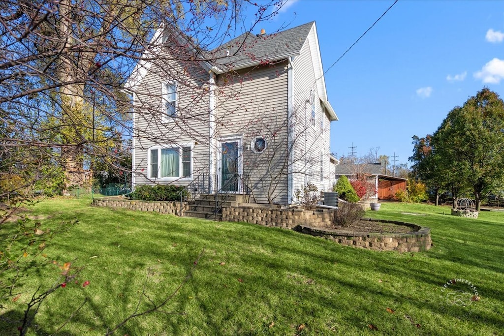 back of house with cooling unit and a lawn