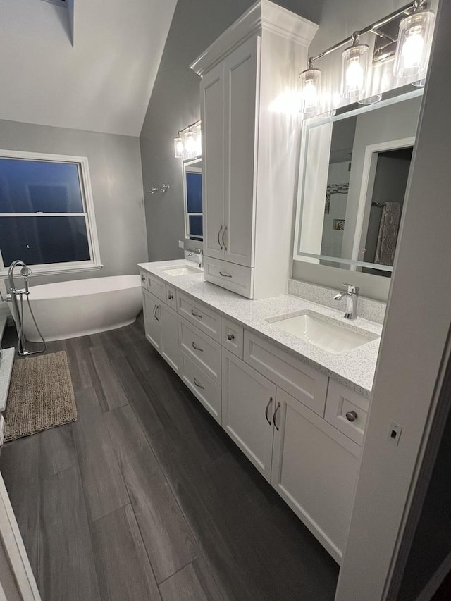 bathroom with hardwood / wood-style flooring, vanity, and lofted ceiling