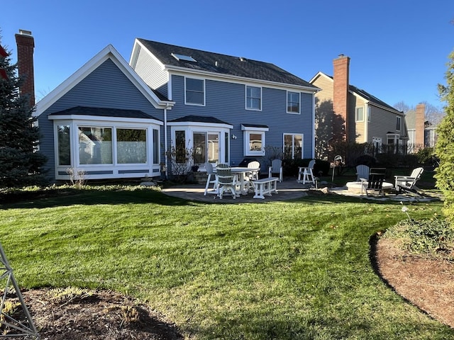 back of property with a yard, a fire pit, and a patio area