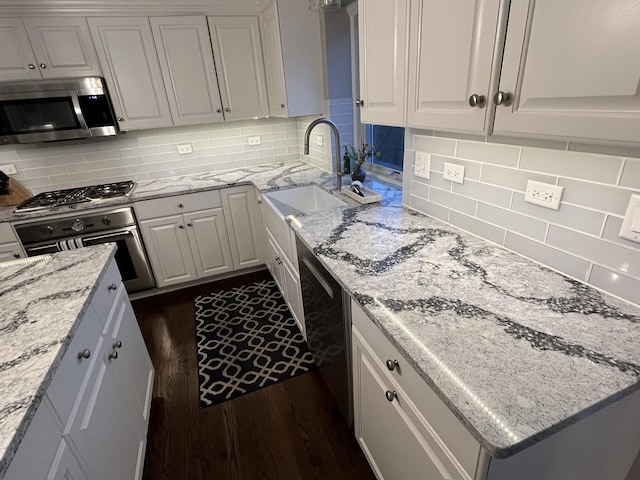 kitchen featuring white cabinets, light stone countertops, stainless steel appliances, and tasteful backsplash