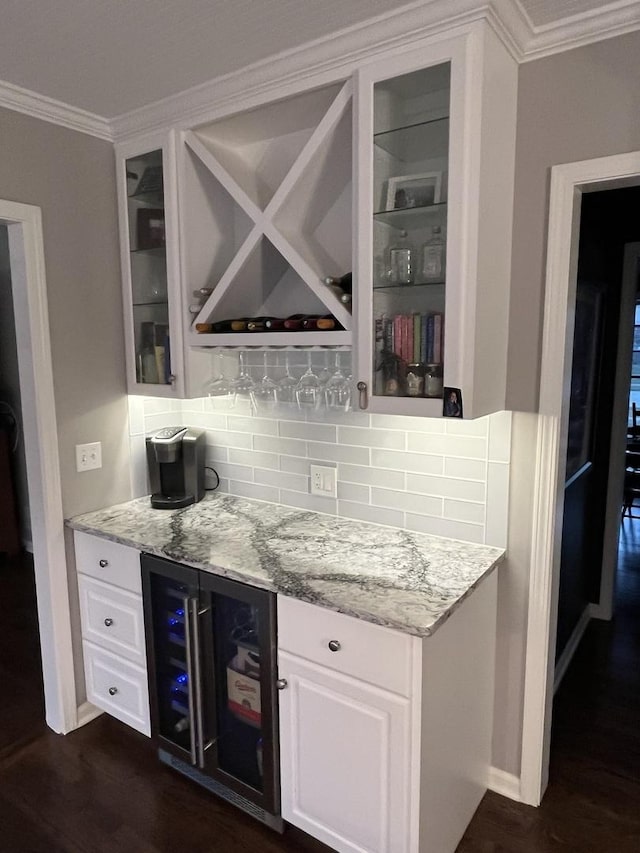 bar with white cabinets, wine cooler, light stone countertops, and ornamental molding