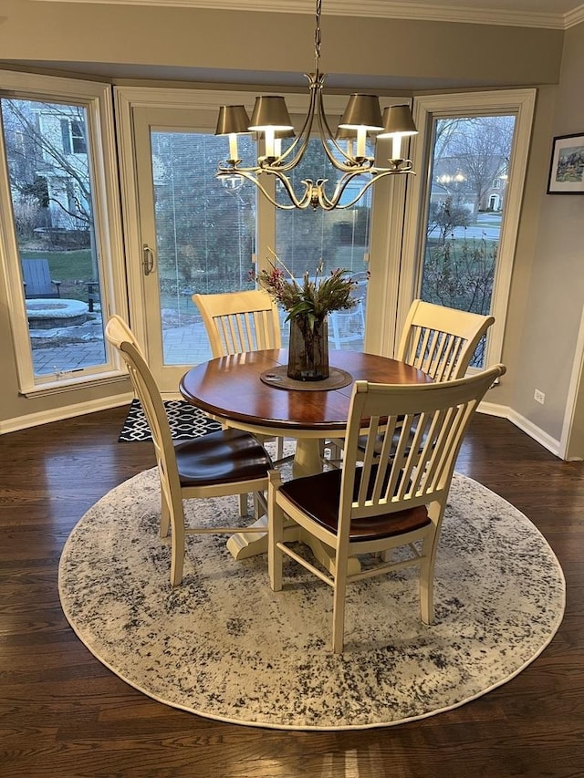 dining room with dark hardwood / wood-style flooring, ornamental molding, and a notable chandelier