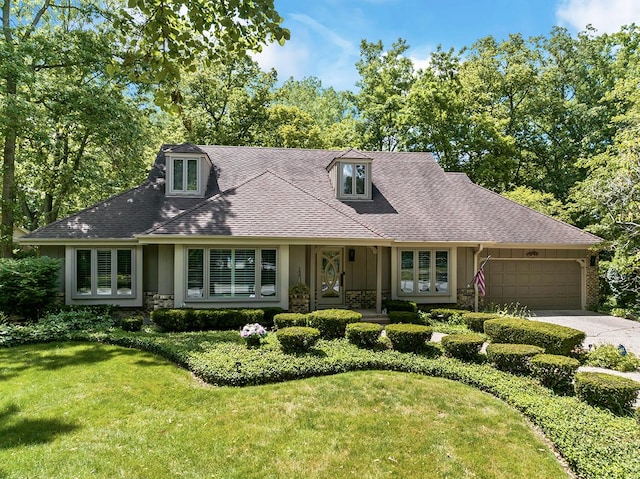 view of front of home featuring an attached garage, concrete driveway, stone siding, roof with shingles, and a front yard