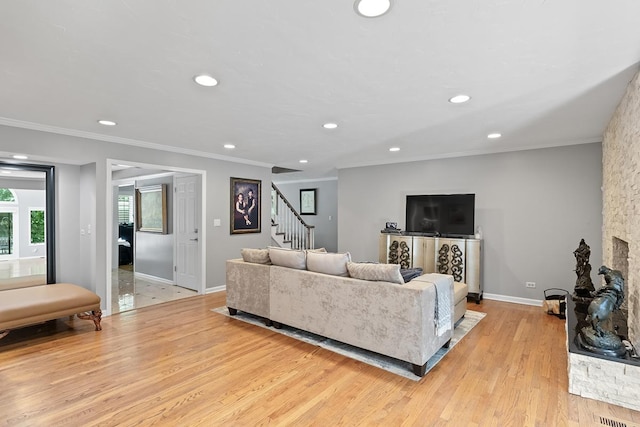 living room with light wood-type flooring, recessed lighting, stairway, and a stone fireplace