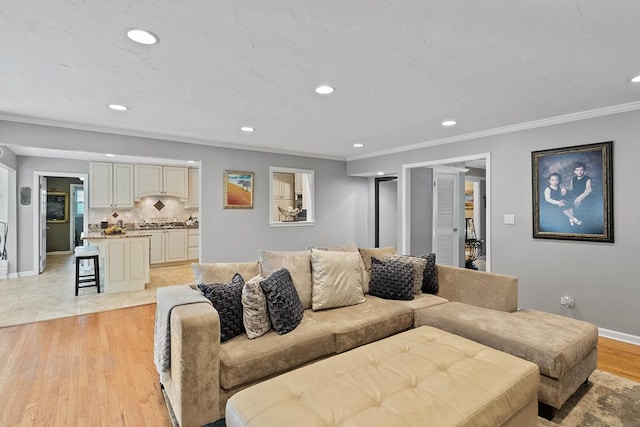living room with ornamental molding, light wood-type flooring, baseboards, and recessed lighting