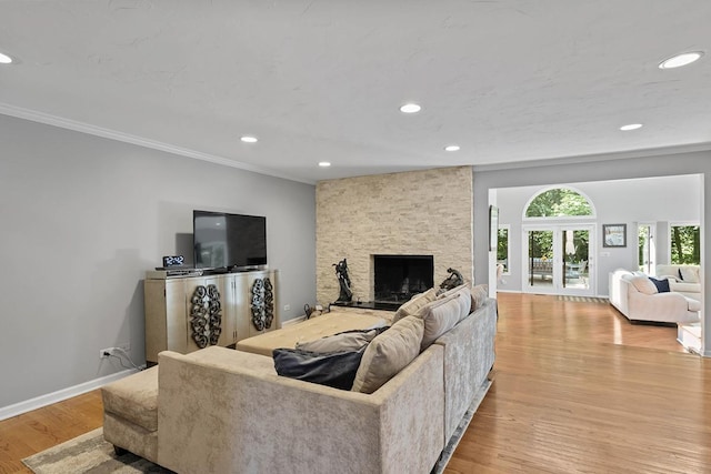 living area featuring ornamental molding, light wood-type flooring, a fireplace, and baseboards