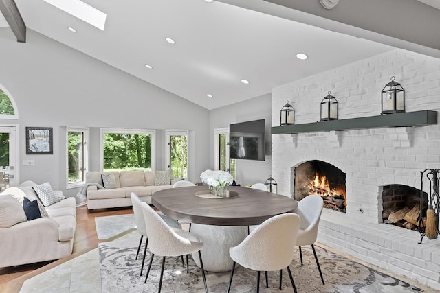 dining space featuring a skylight, a fireplace, light wood finished floors, recessed lighting, and high vaulted ceiling