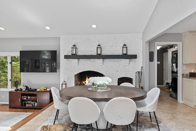 dining room with baseboards, stacked washer / dryer, a brick fireplace, and recessed lighting