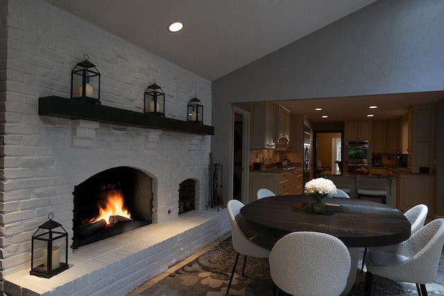 dining space with recessed lighting, vaulted ceiling, and a fireplace