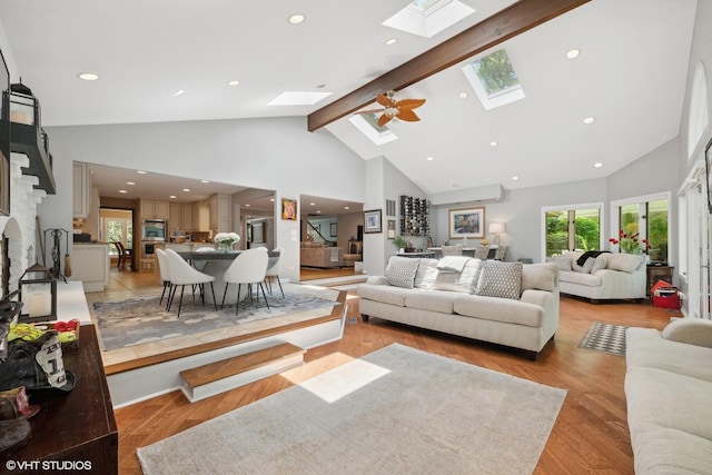 living room featuring high vaulted ceiling, a skylight, beam ceiling, and light wood-style flooring