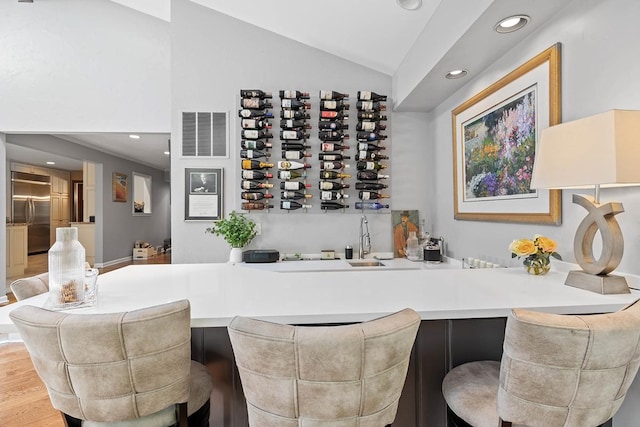 bar featuring recessed lighting, visible vents, vaulted ceiling, wood finished floors, and built in refrigerator