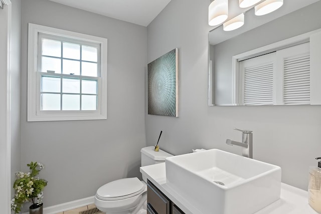 half bathroom featuring toilet, visible vents, baseboards, and vanity