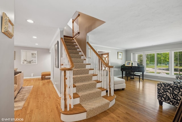 stairs with recessed lighting, crown molding, baseboards, and wood finished floors