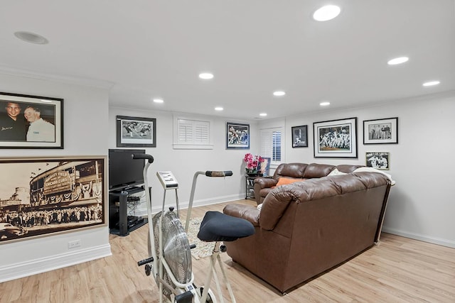 living area featuring light wood-style floors, baseboards, and crown molding