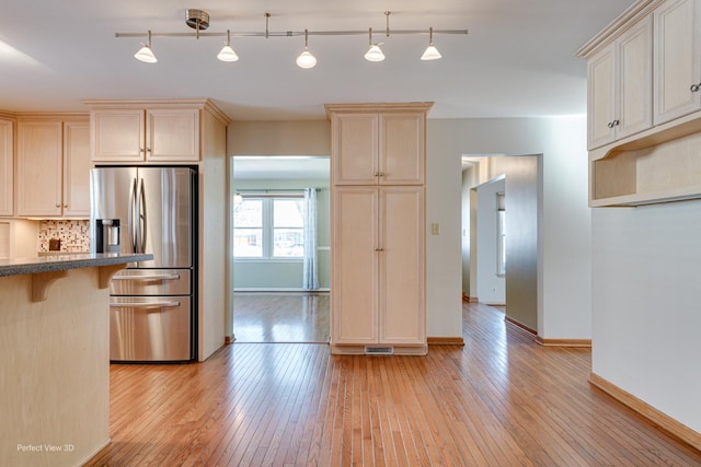 kitchen featuring a breakfast bar area, light hardwood / wood-style floors, stainless steel fridge, and hanging light fixtures