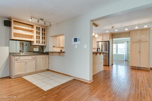 kitchen featuring decorative backsplash, stainless steel fridge, sink, and light hardwood / wood-style floors