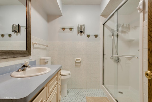 bathroom with toilet, tile patterned flooring, tile walls, an enclosed shower, and vanity