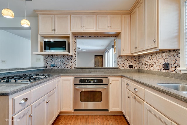 kitchen featuring hanging light fixtures, light wood-type flooring, tasteful backsplash, and stainless steel appliances