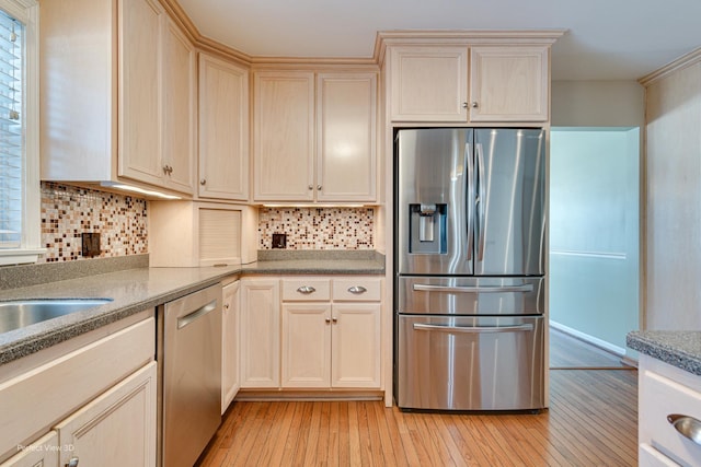 kitchen with light wood-type flooring, appliances with stainless steel finishes, and decorative backsplash