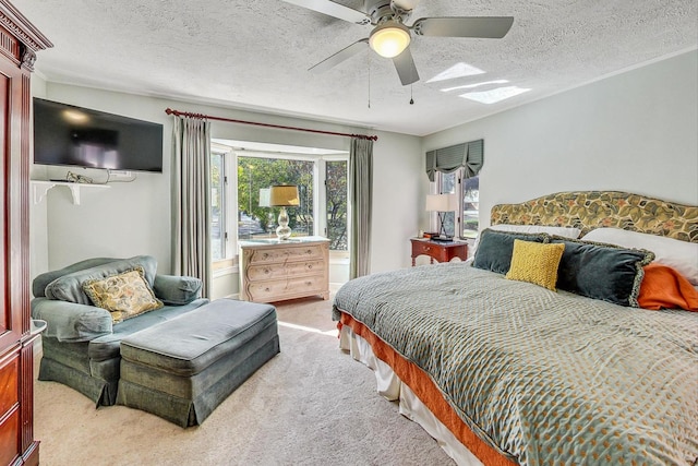 bedroom featuring a textured ceiling, light colored carpet, and ceiling fan