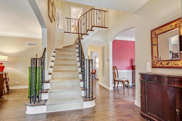 staircase featuring ornamental molding and hardwood / wood-style floors