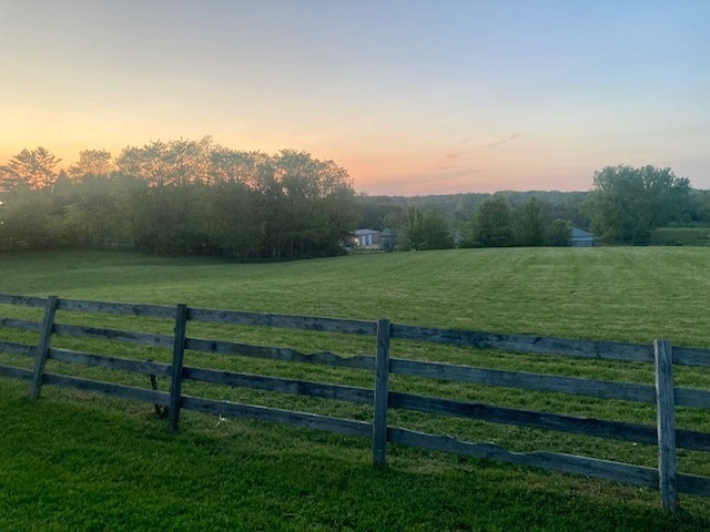 gate at dusk featuring a lawn and a rural view