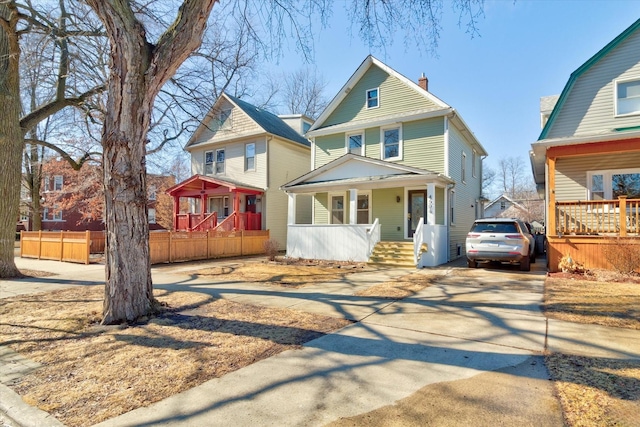 view of front of home featuring covered porch, a chimney, fence, and concrete driveway