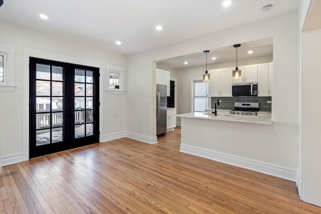 kitchen with stainless steel appliances, white cabinets, hanging light fixtures, light countertops, and french doors