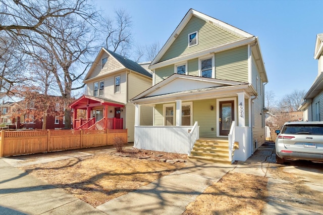 american foursquare style home with covered porch and fence