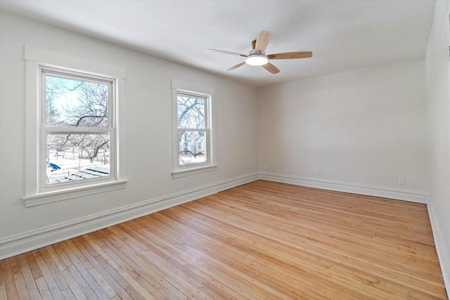 empty room featuring light wood-style floors, baseboards, and a ceiling fan