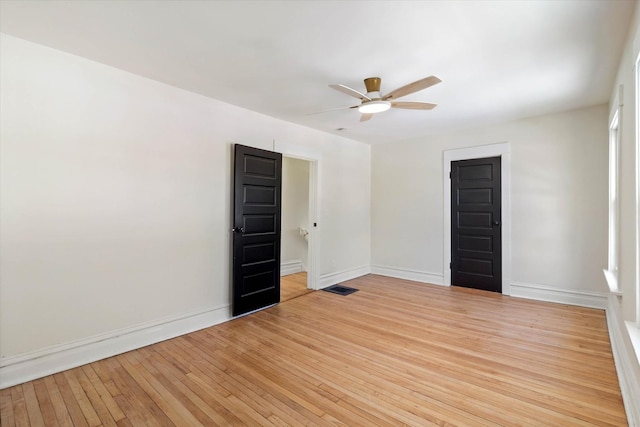 unfurnished room featuring light wood finished floors, baseboards, visible vents, and a ceiling fan