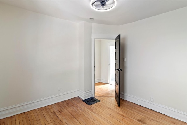 unfurnished room with wood-type flooring, visible vents, and baseboards