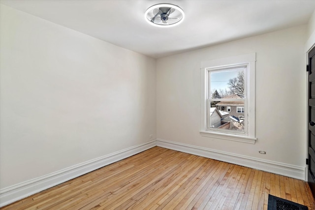 spare room with light wood finished floors, visible vents, and baseboards