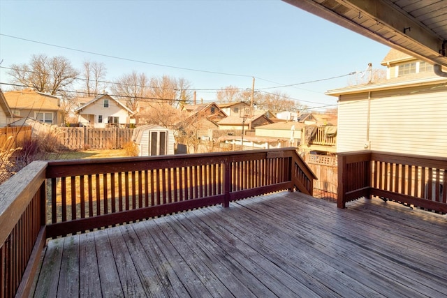 wooden deck with a residential view, an outdoor structure, fence, and a storage unit