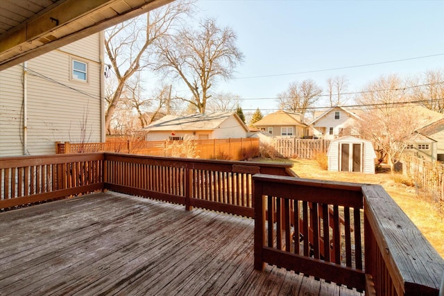 deck with a storage shed, a fenced backyard, a residential view, and an outdoor structure